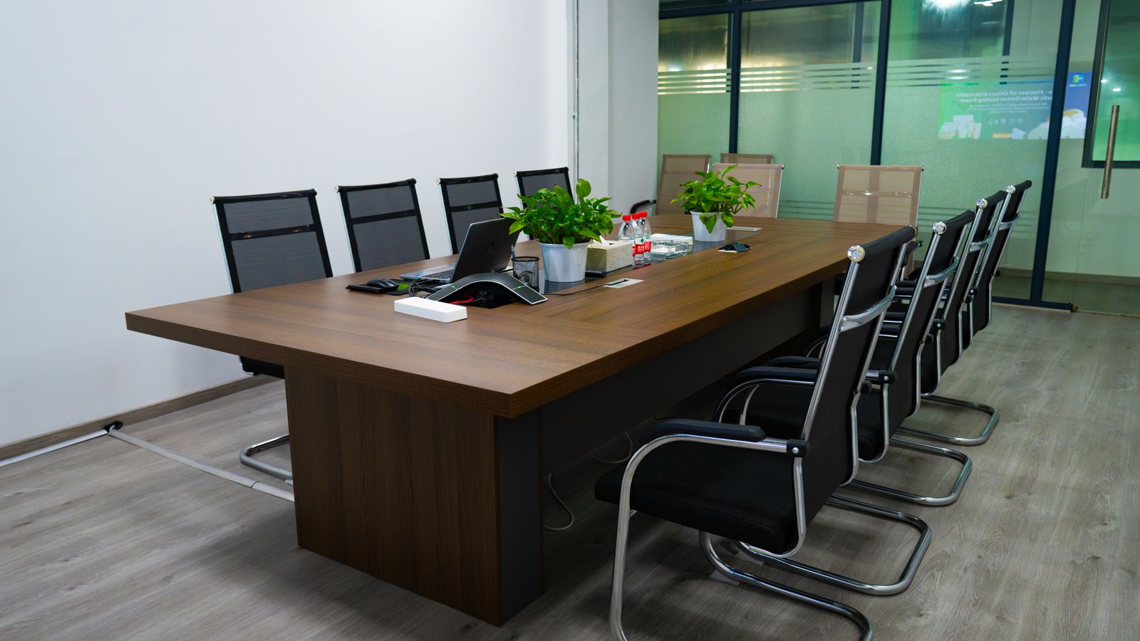 An empty meeting room with a long wooden table, chairs and plants