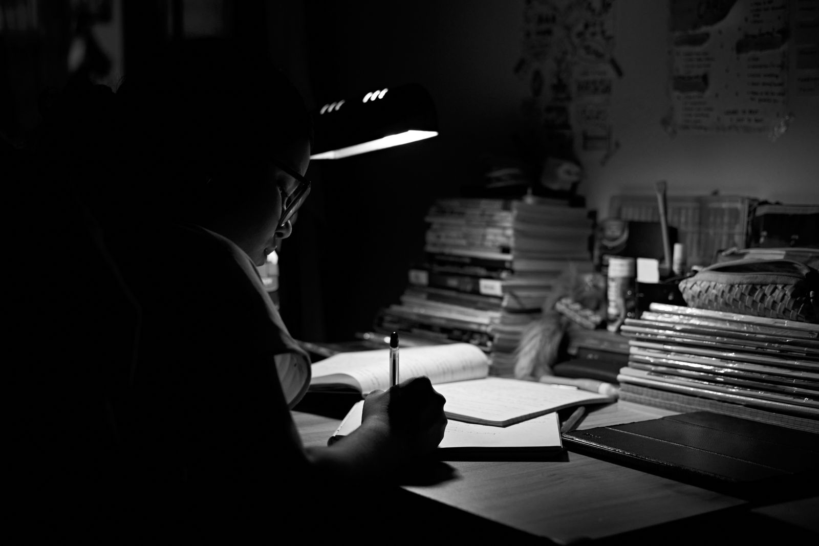Eine Person schreibt nachts bei Lampenlicht an einem Schreibtisch