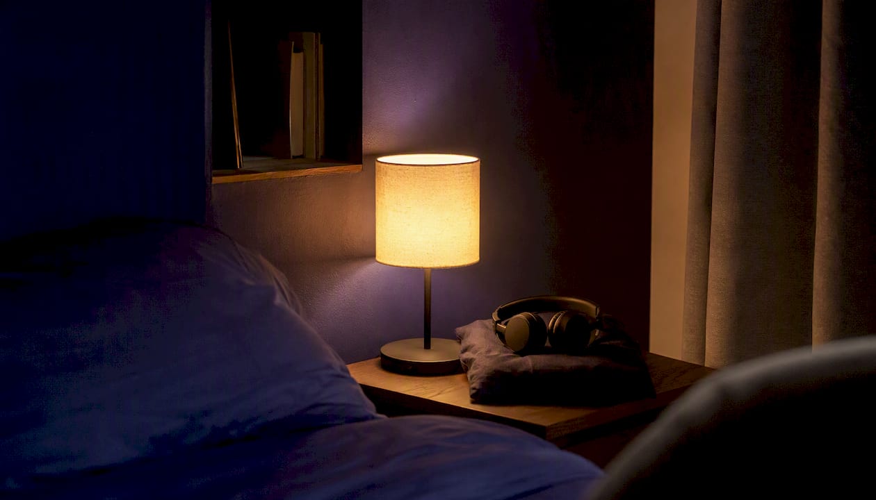 Kopfhörer auf den Ohren und ein sanftes Nachtlicht tauchen das dunkle Zimmer in eine gemütliche Atmosphäre.