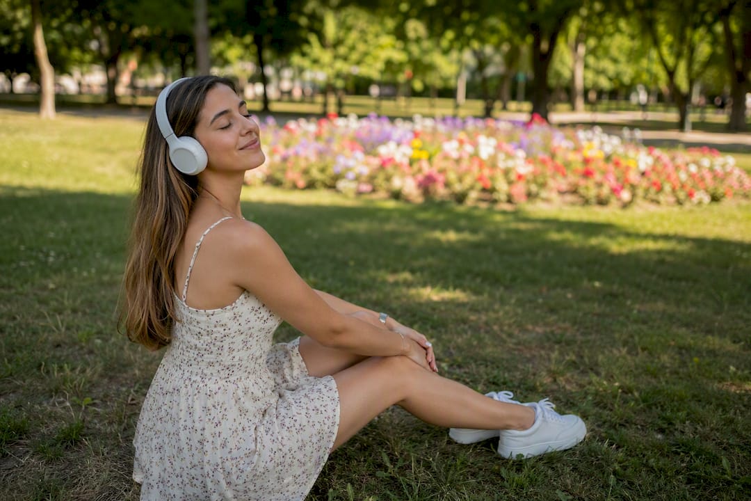 Frau hört draußen mit Kopfhörern Audio