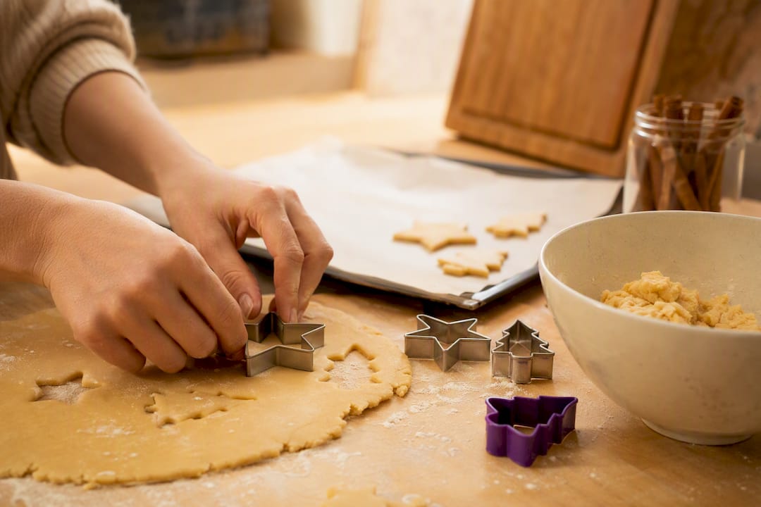 Hände stechen Weihnachtsplätzchen aus